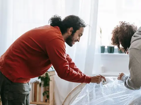 A couple wrapping furniture in bubble wrap before a move