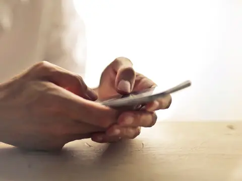 Hands holding a smartphone over a table in soft light