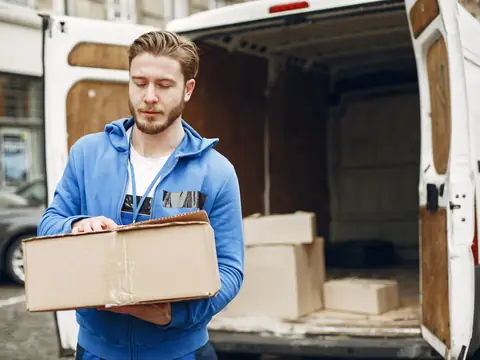 A man carrying a cardboard box beside an open van