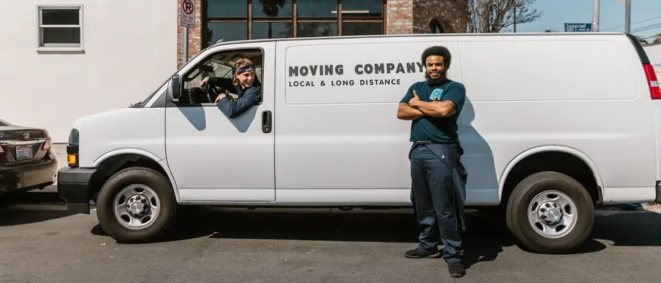 Two movers beside their white van on a sunny city street
