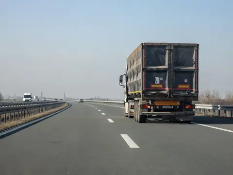 A cargo truck driving down an empty highway on a clear day