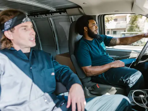 Two movers in the cab of their moving van