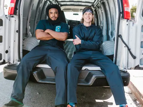 Two movers sitting in the open back of their white van
