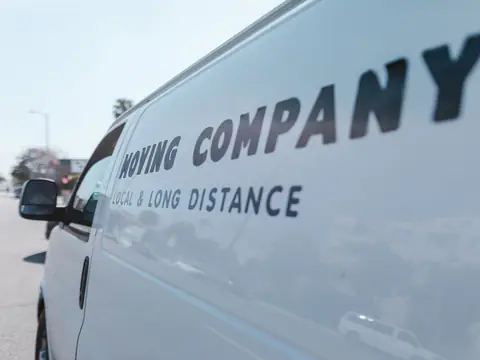 Close-up of the lettering on the side of a white moving van on a sunny street